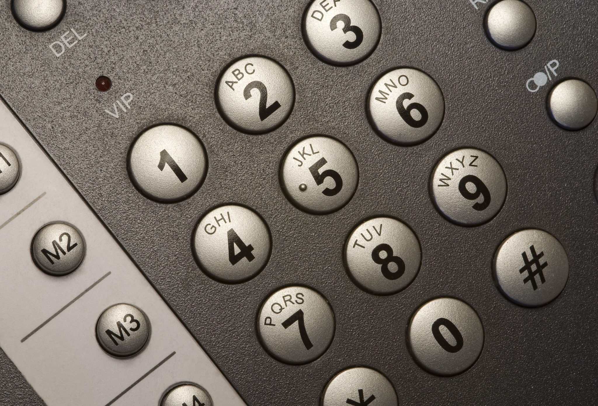 Close-up of a keypad with round gray number keys labeled with letters (2–9) and adjacent function keys visible on a textured surface