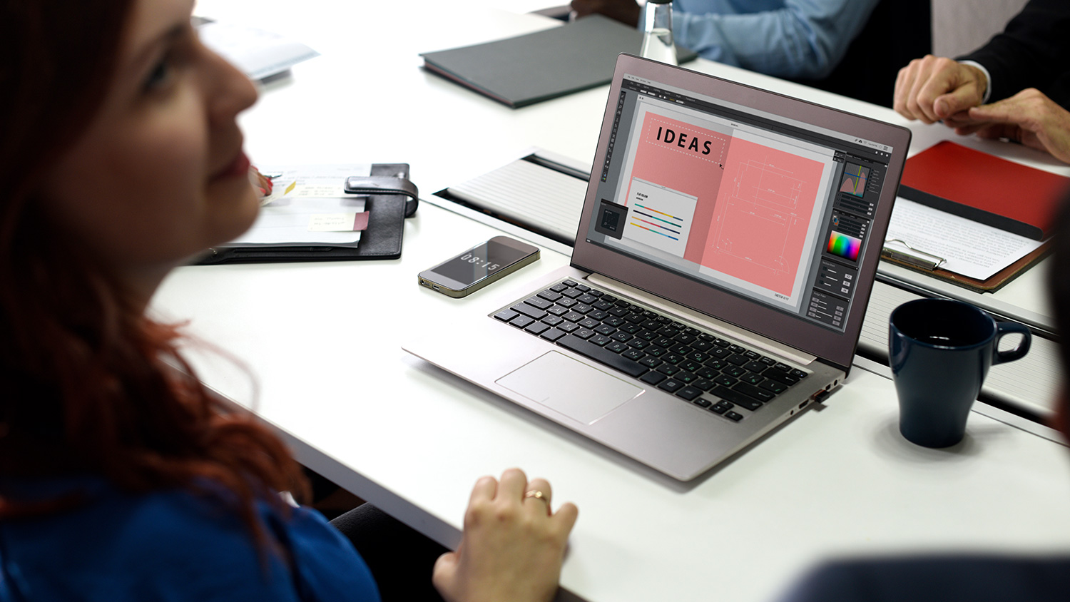 people at meeting with laptop open on table