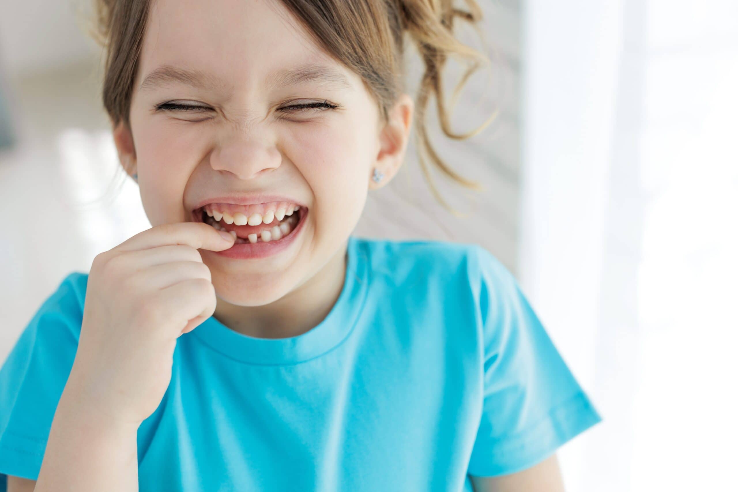 Fillette souriante montrant sa dent de lait tombée