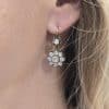 Diamond flower drop earring in gold, showcasing sparkling gemstones.