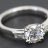 Elegant diamond engagement ring with a central round cut stone and baguette side stones.