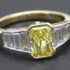 Stunning yellow diamond engagement ring with baguette-cut diamonds in gold setting.