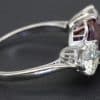 Silver ring with a large red ruby and two side diamonds, crafted for special occasions.