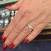 Stunning emerald cut diamond engagement ring on a woman's hand with red nails.