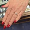 Engagement ring with a sparkling center stone on a woman's hand with red nail polish.