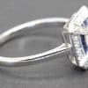 Engagement ring with a central diamond and blue sapphires, set in a silver band.