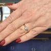 Diamond engagement ring on a woman's hand with red nail polish.