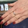 Diamond engagement ring on woman's hand with red nail polish.