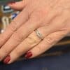 Diamond engagement ring on woman's finger, showcasing fine jewelry craftsmanship.