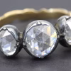 Diamond ring with three large, clear gemstones and a gold band.