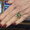 Elegant green gemstone ring on a woman's finger, showcasing fine jewelry craftsmanship.