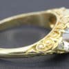 Gold ring with detailed scrollwork and a sparkling central diamond.