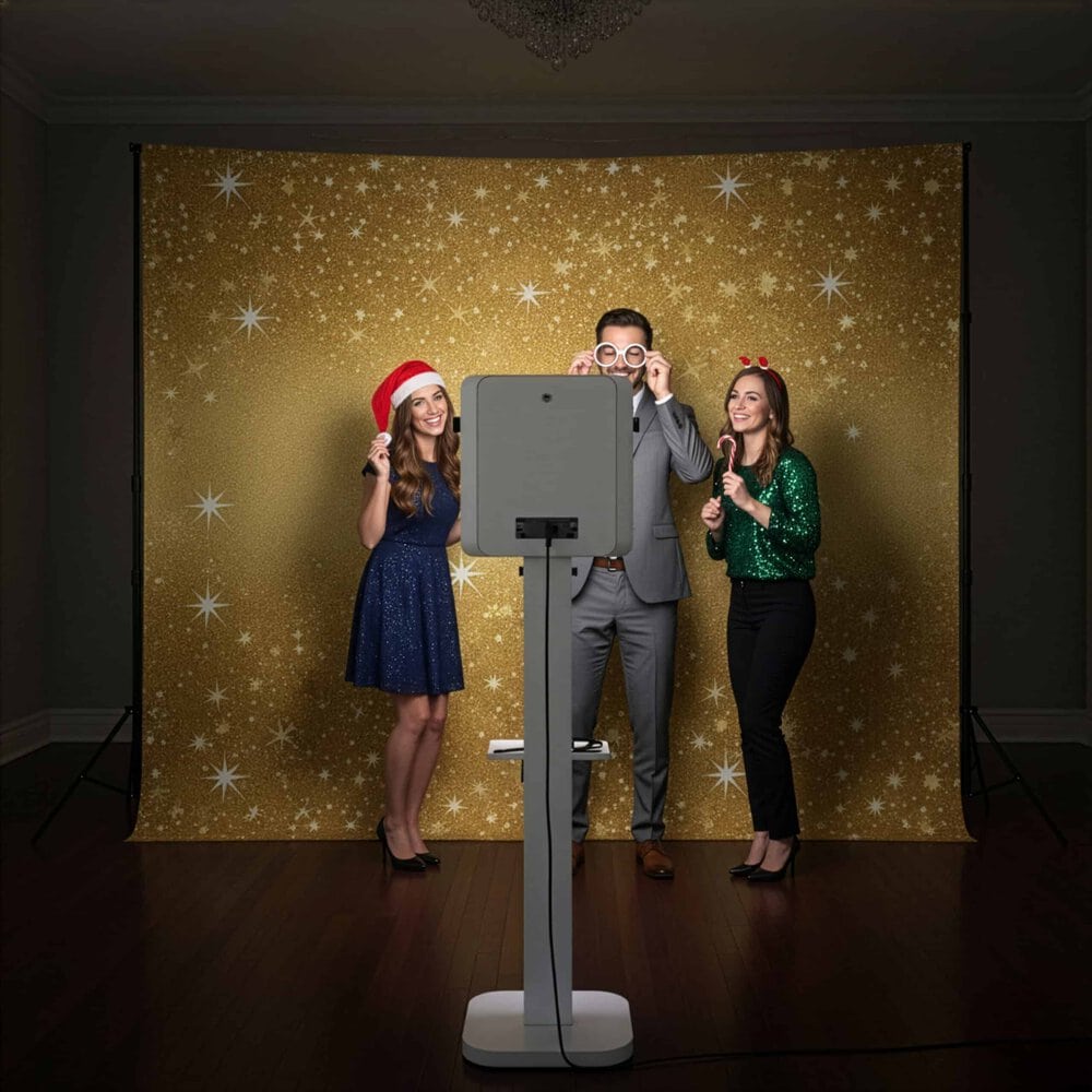 Fotobox mit goldenem Hintergrund und drei Gästen
