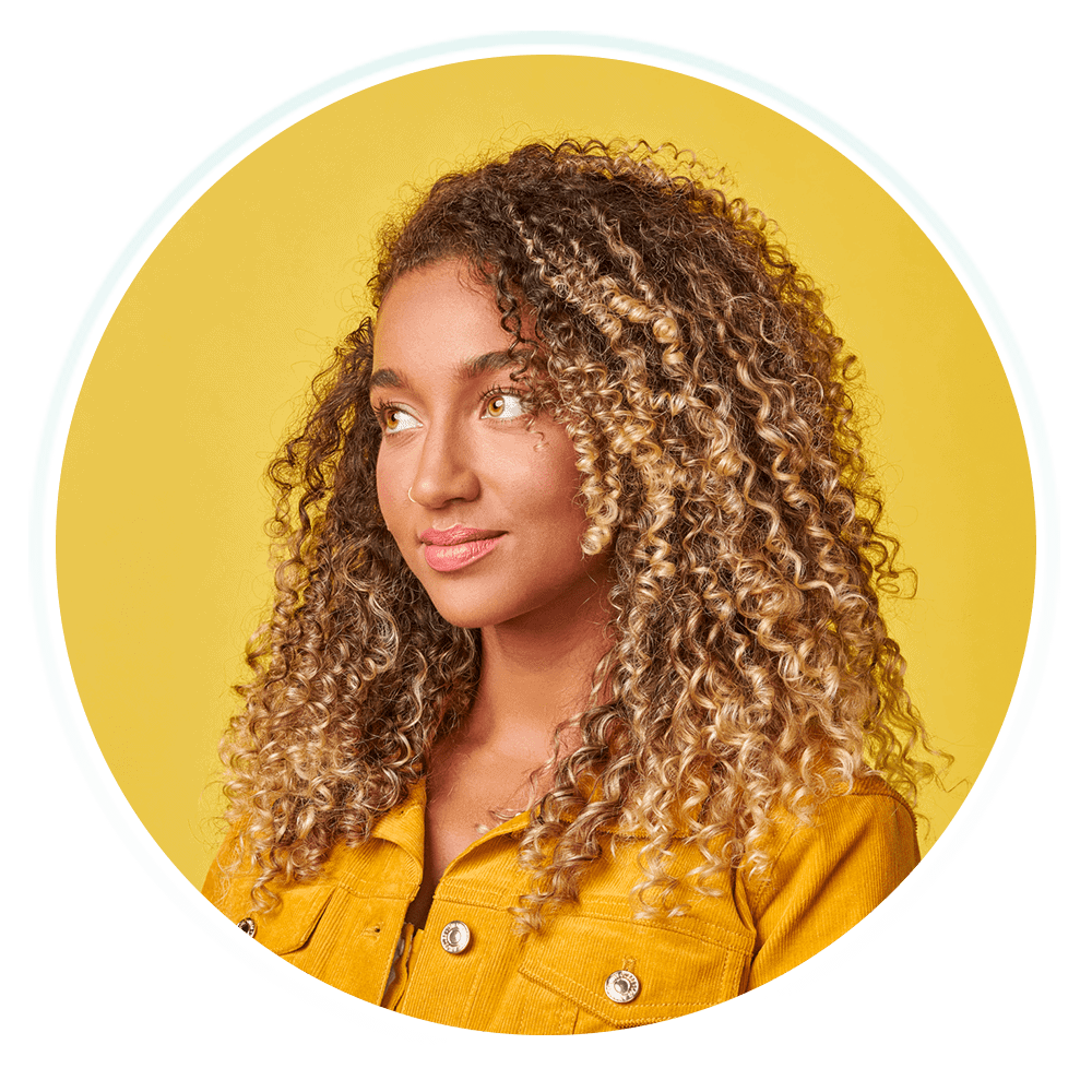 A young woman with curly hair, radiating positivity and confidence.