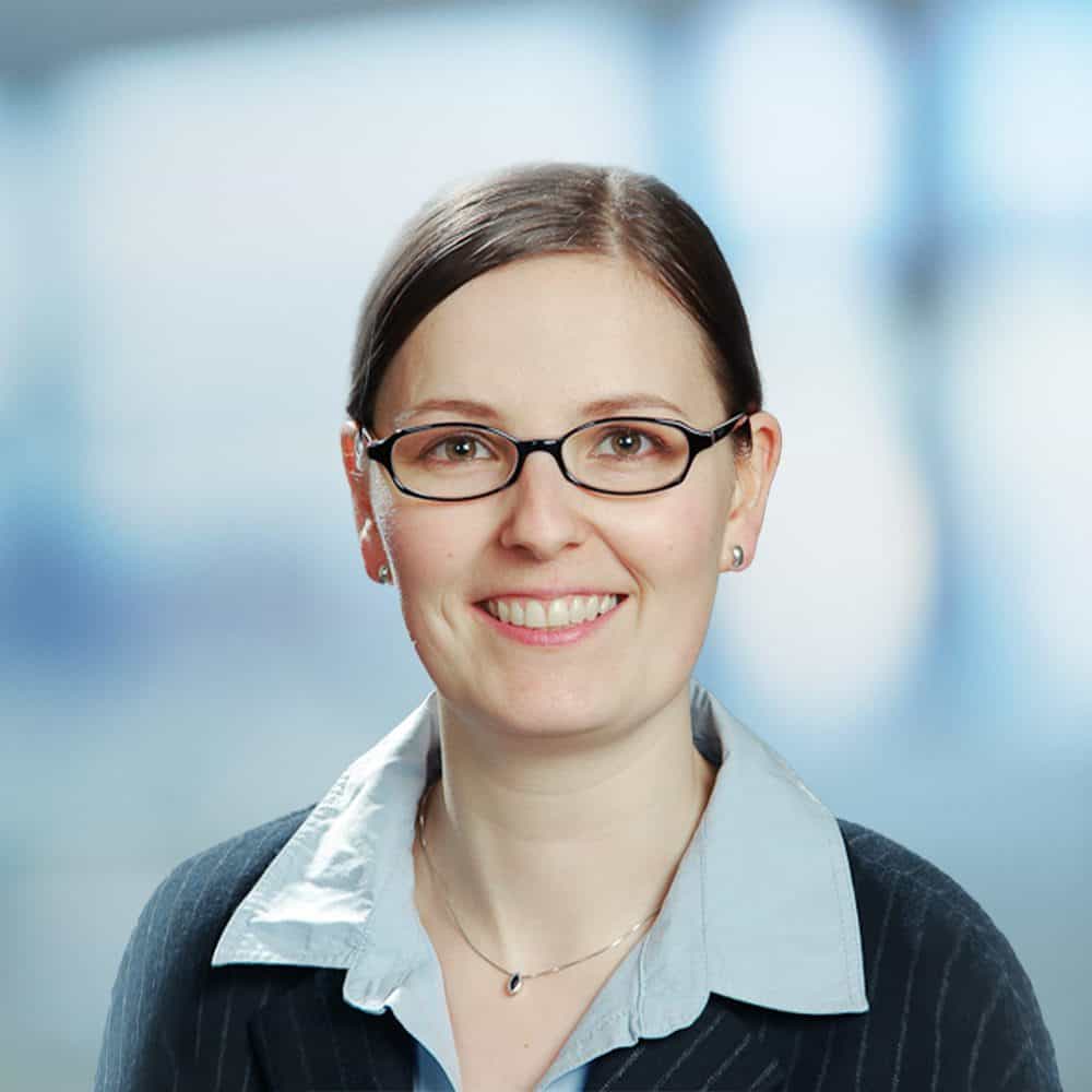 Professionelle Frau bei ITB Karlsruhe im Business-Meeting, lächelnd, mit Brille.