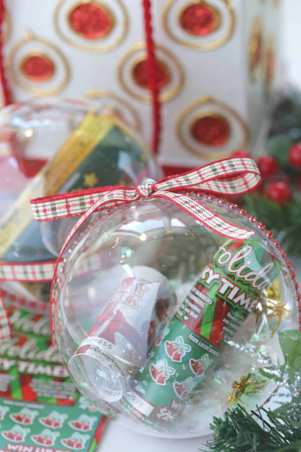 Gift the gift of lottery luck this holiday season with these fun New Jersey Lottery Ticket Christmas Ornaments. These DIY Christmas ornaments are easy to make. Grab some lottery ytickets and fill a plastic ornament. This easy Christmas craft takes only a few minutes to make. These ornaments are fun to hang on the Christmas Tree. Lottery Ticket ornaments make a great Christmas gift idea too.