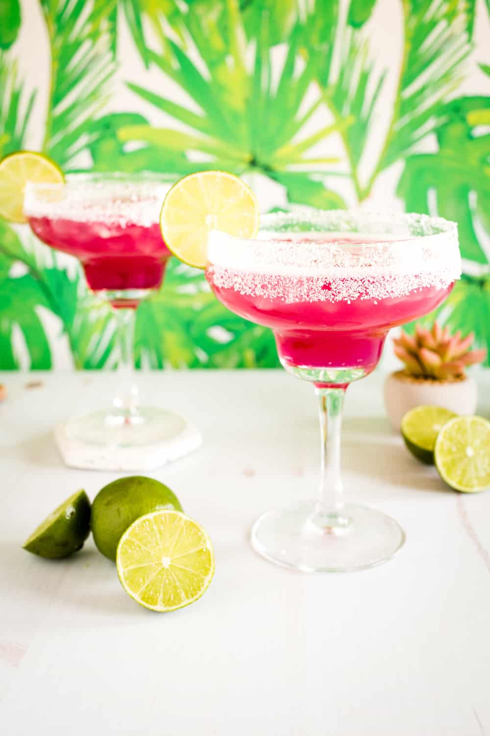 pink prickly pear margaritas surrounded by limes