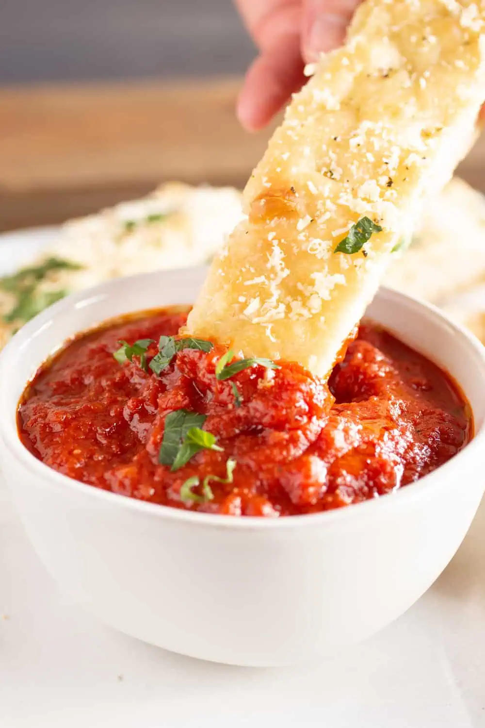 crock of marinara sauce with breadstick dipping in