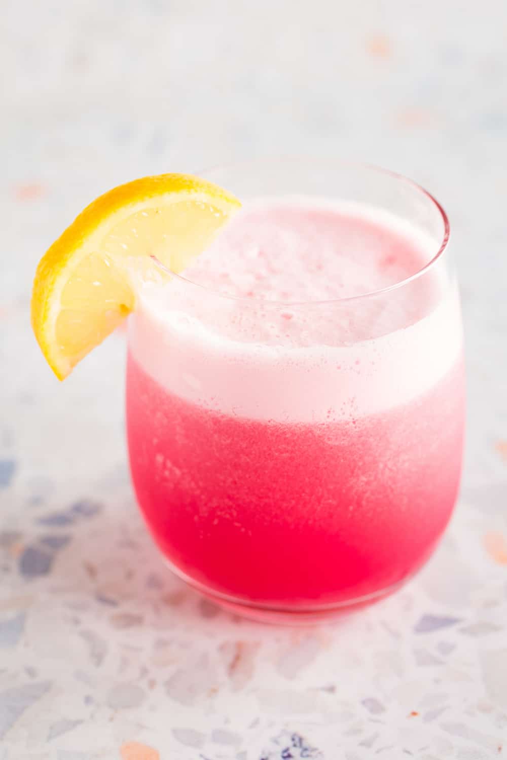rhubarb gin fizz cocktail with lemon wedge garnish