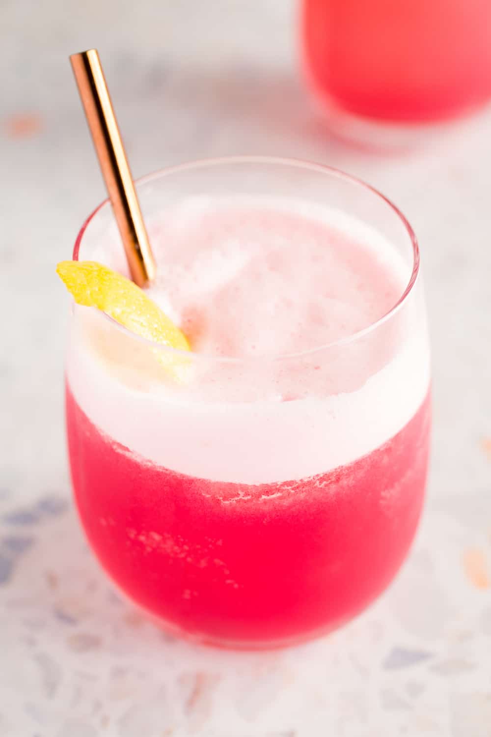 rhubarb gin fizz cocktail with lemon twist garnish