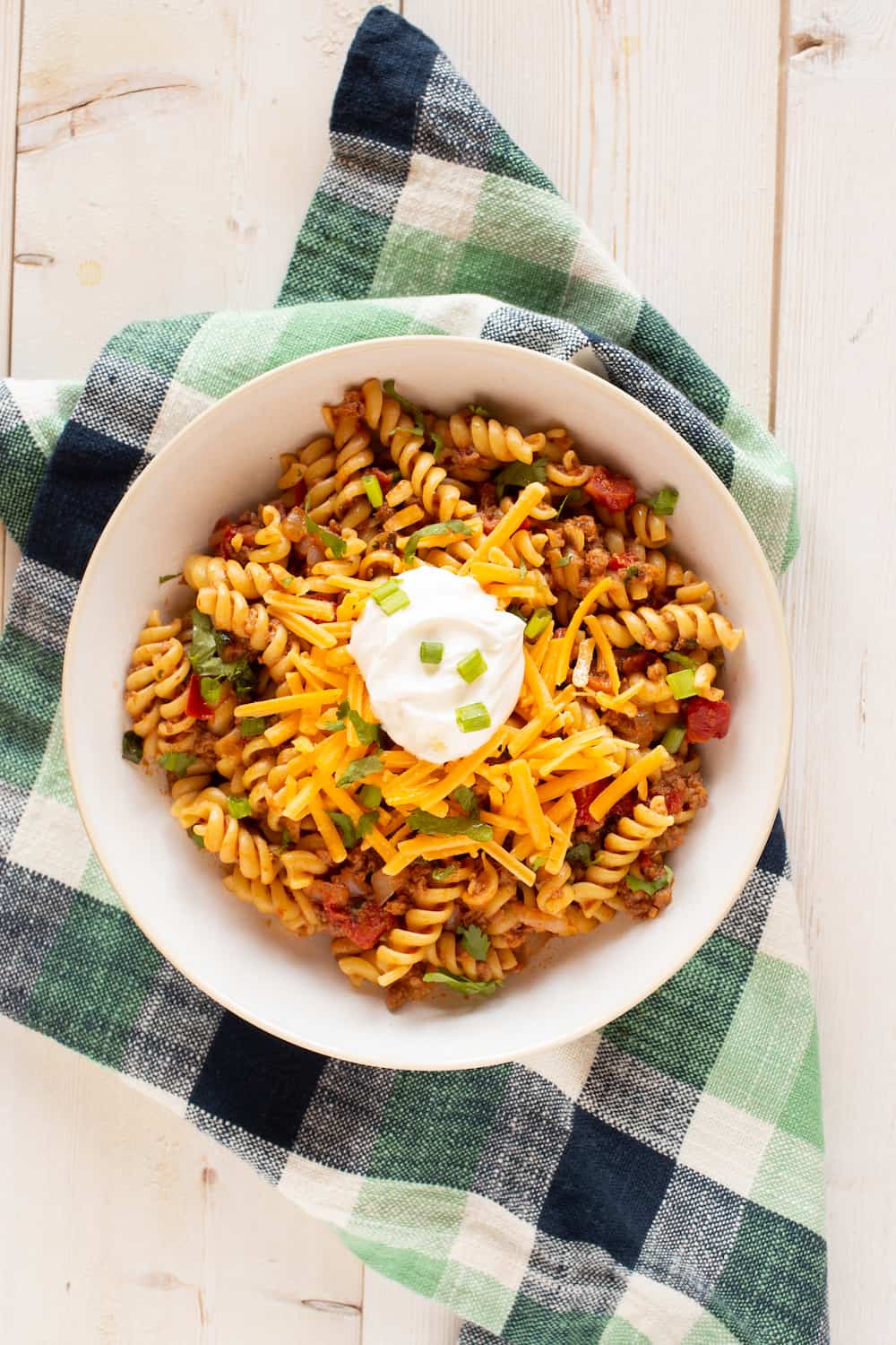 bowl of taco pasta topped with cheese and sour cream