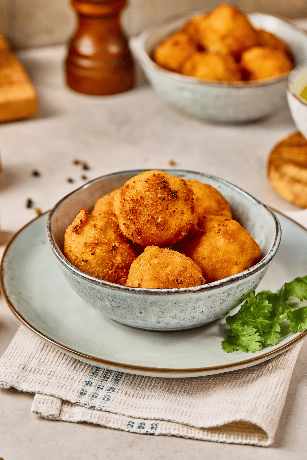 A blue bowl filled with fried Mac and Cheese Bites garnished with fresh parsley on a neutral cloth napkin.
