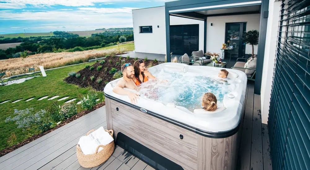 Une famille se détend dans un spa installé contre leur maison avec vue sur le jardin.