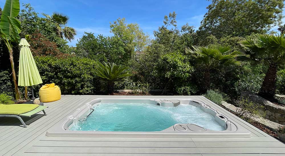 Spa de nage encastré dans une terrasse et entouré de verdure