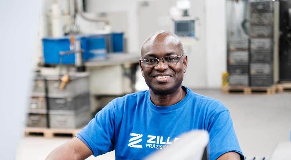 Mitarbeiter an einer Feder-Endbearbeitungsmaschine, die eine präzise Oberflächenbehandlung durchführt.