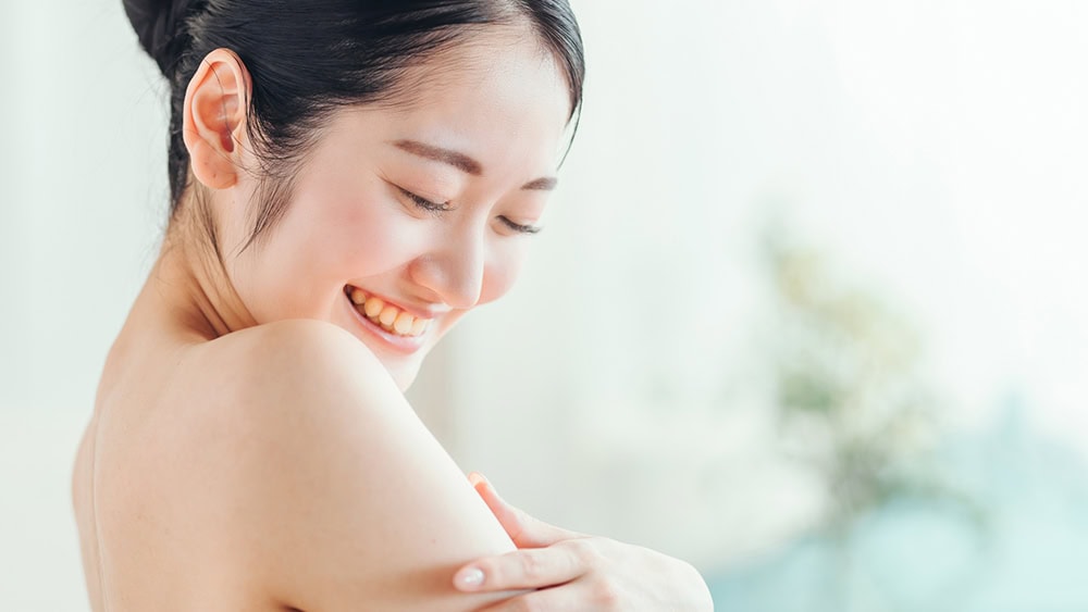 笑顔で素肌に触れる女性