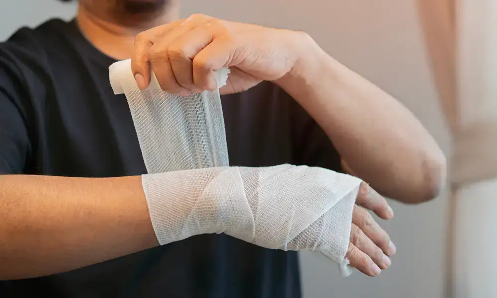 Mężczyzna bandażujący sobie rękę - zdjęcie.