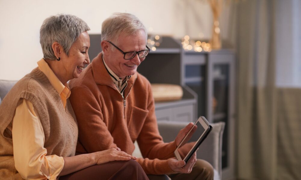 couple smiling while looking at a tablet computer