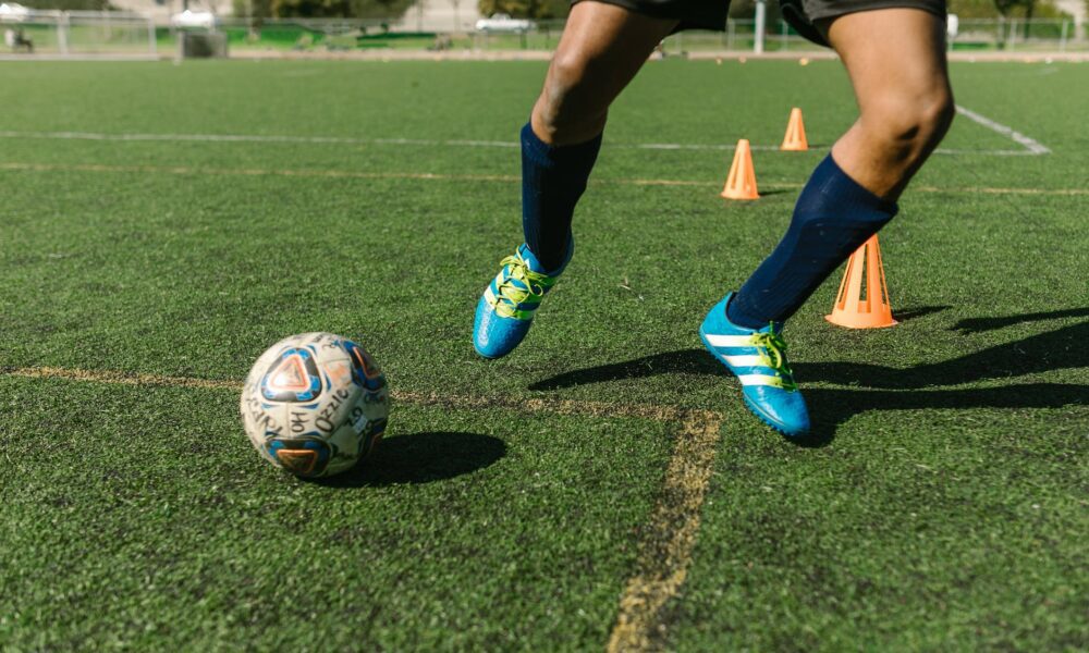 man in blue sneakers playing football