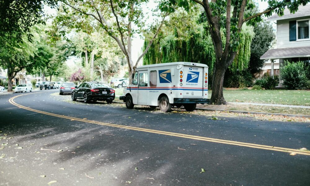 a white van parked on the roadside near tree, Mailing
