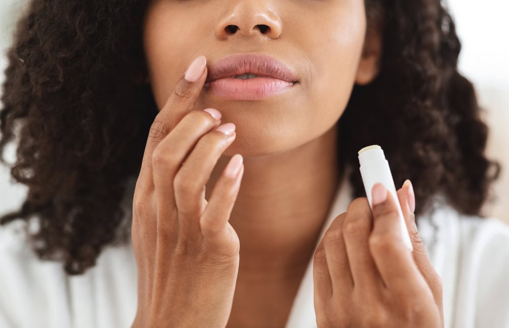 Women putting on lip balm in white robe - beauty habits