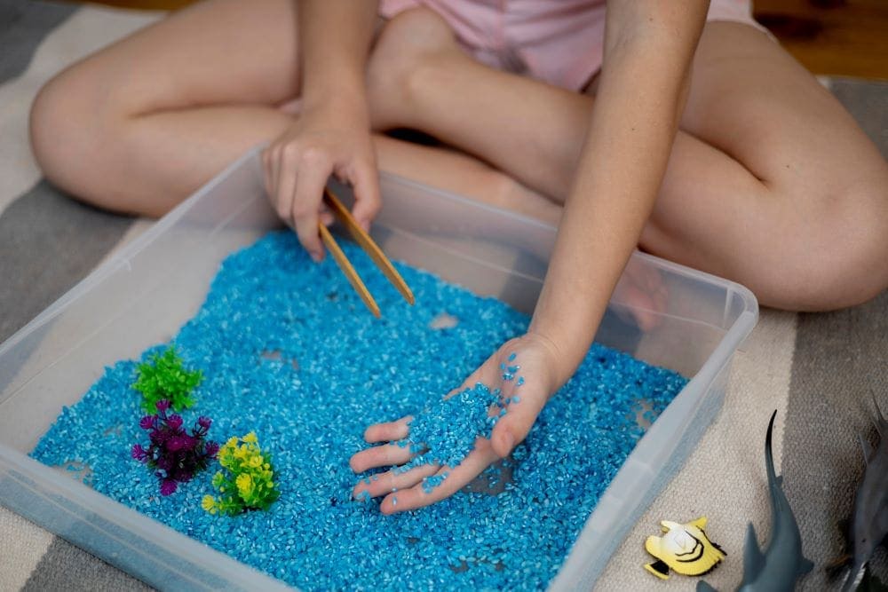 Blue colored rice in a bin for an ocean themed sensory bin