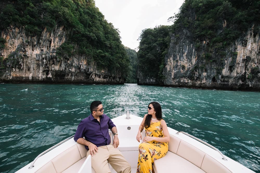 Couple on a boat surrounded by limestone cliffs and green water in Krabi