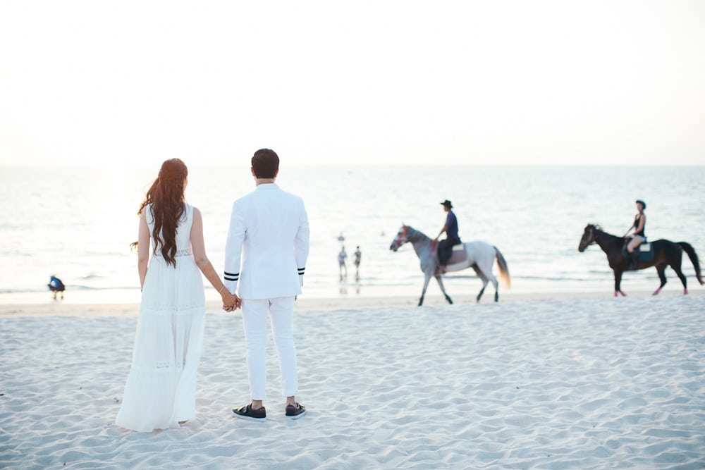 Couple dressed in white looking out to sea on a Phuket beach