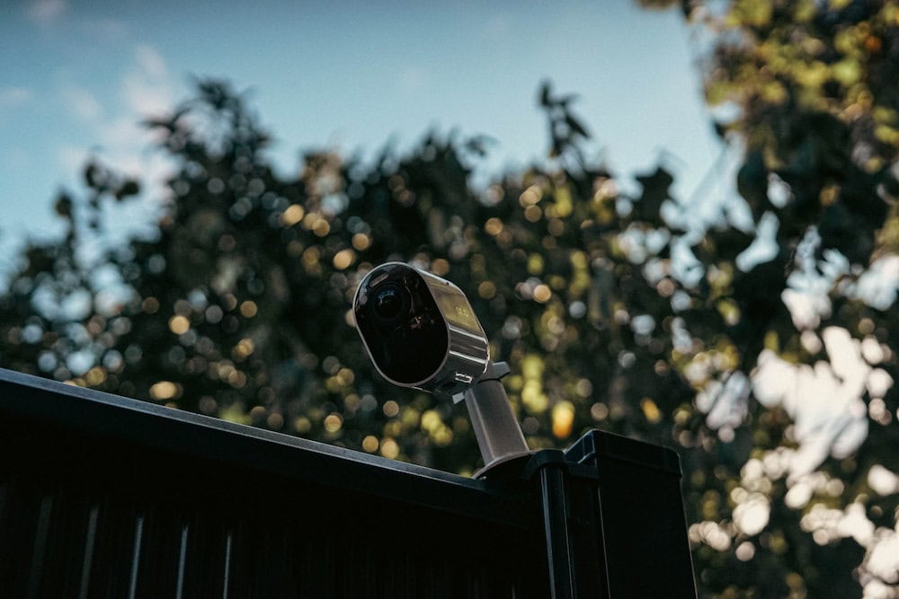A camera perched on top of a home facing the front lawn.