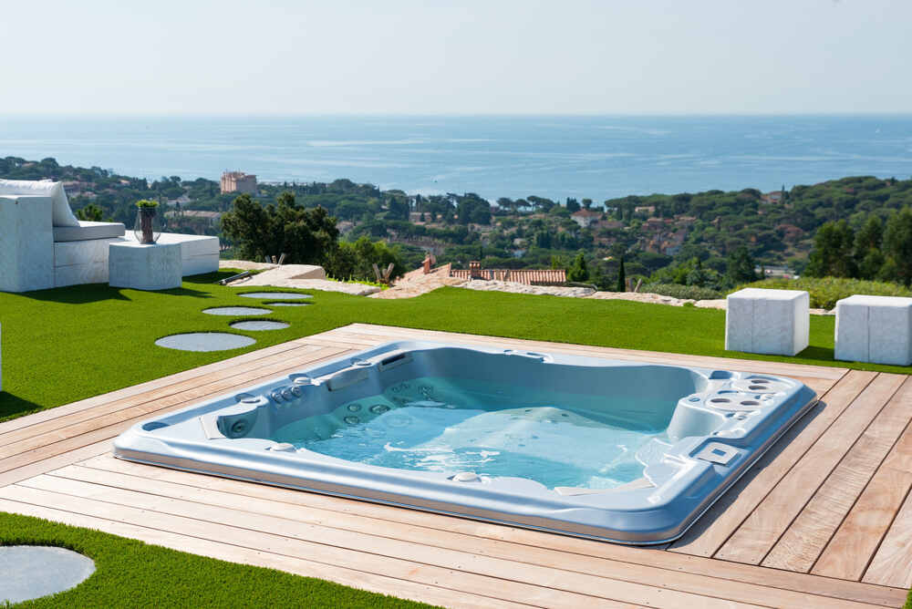 Un spa est encastré dans une terrasse et bénéficie d'une vue mer.