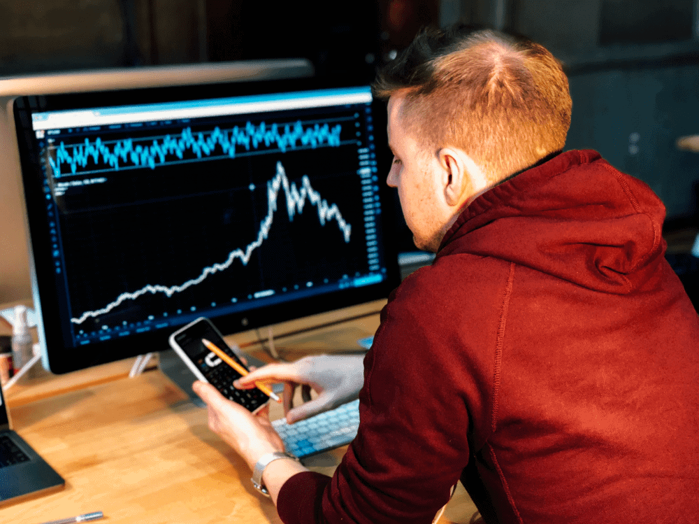Investor watching a computer screen displaying a fluctuating stock market chart, illustrating psychological attachment to an average stock price.