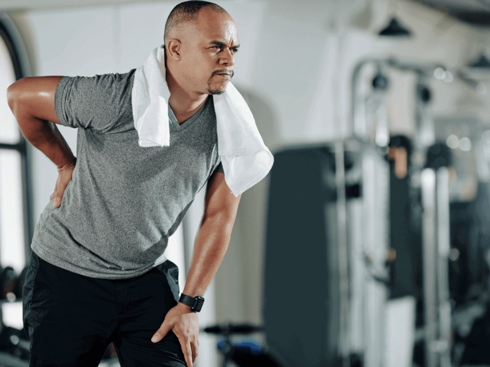 Man experiencing lower back discomfort in gym — Low Back Pain Training Los Angeles at Body360 Fit