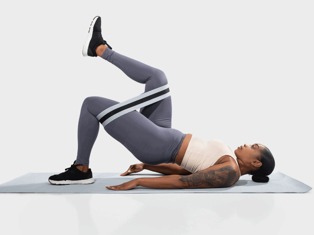 Client performs a banded single-leg glute bridge exercise to strengthen her hamstrings and glutes - Low Back Training Los Angeles - Body360 Fit