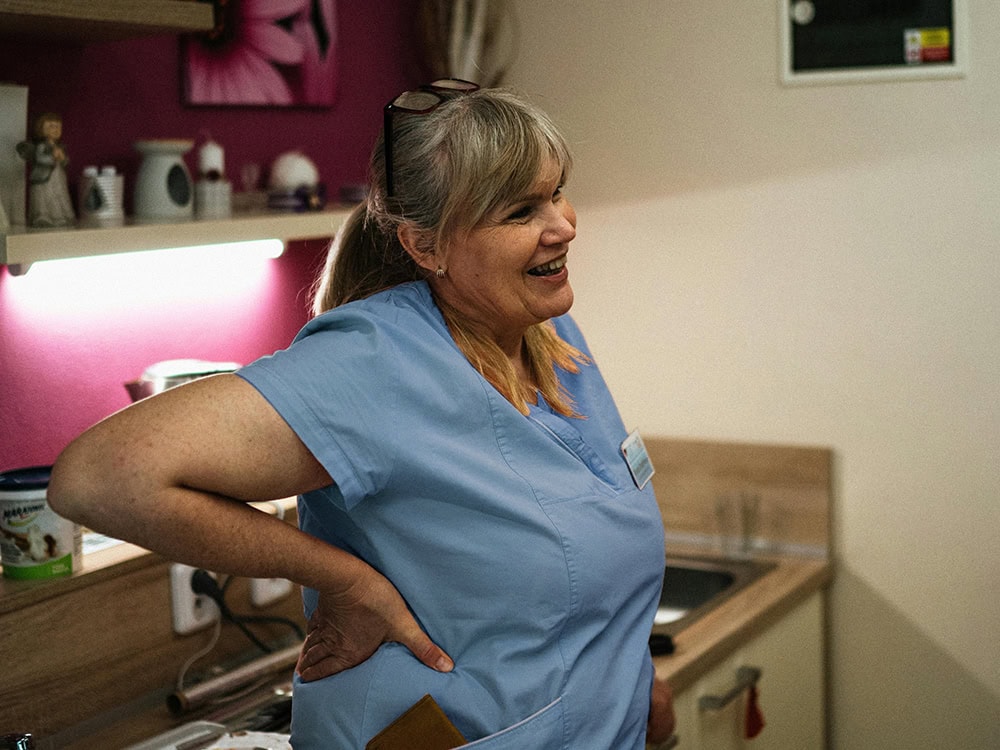 nurse-leaning-smiling-pinkscrubs A middle-aged nurse leaning casually and smiling