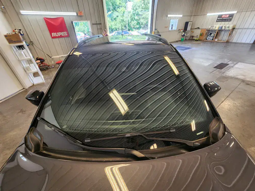 Close-up view of a vehicle windshield receiving high-performance ceramic window tinting at the Valion Tinting professional workshop in Kansas City