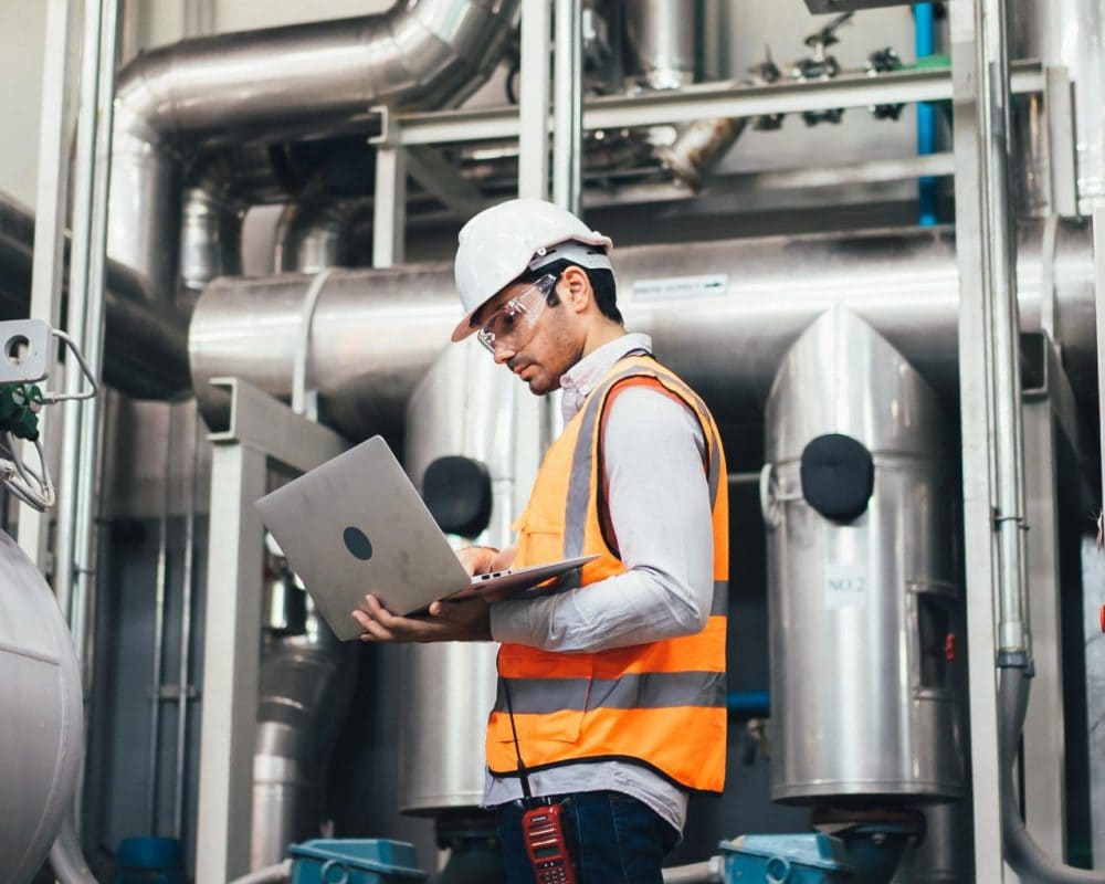Tècnic revisant una instal·lació de gas natural en una planta industrial amb portàtil