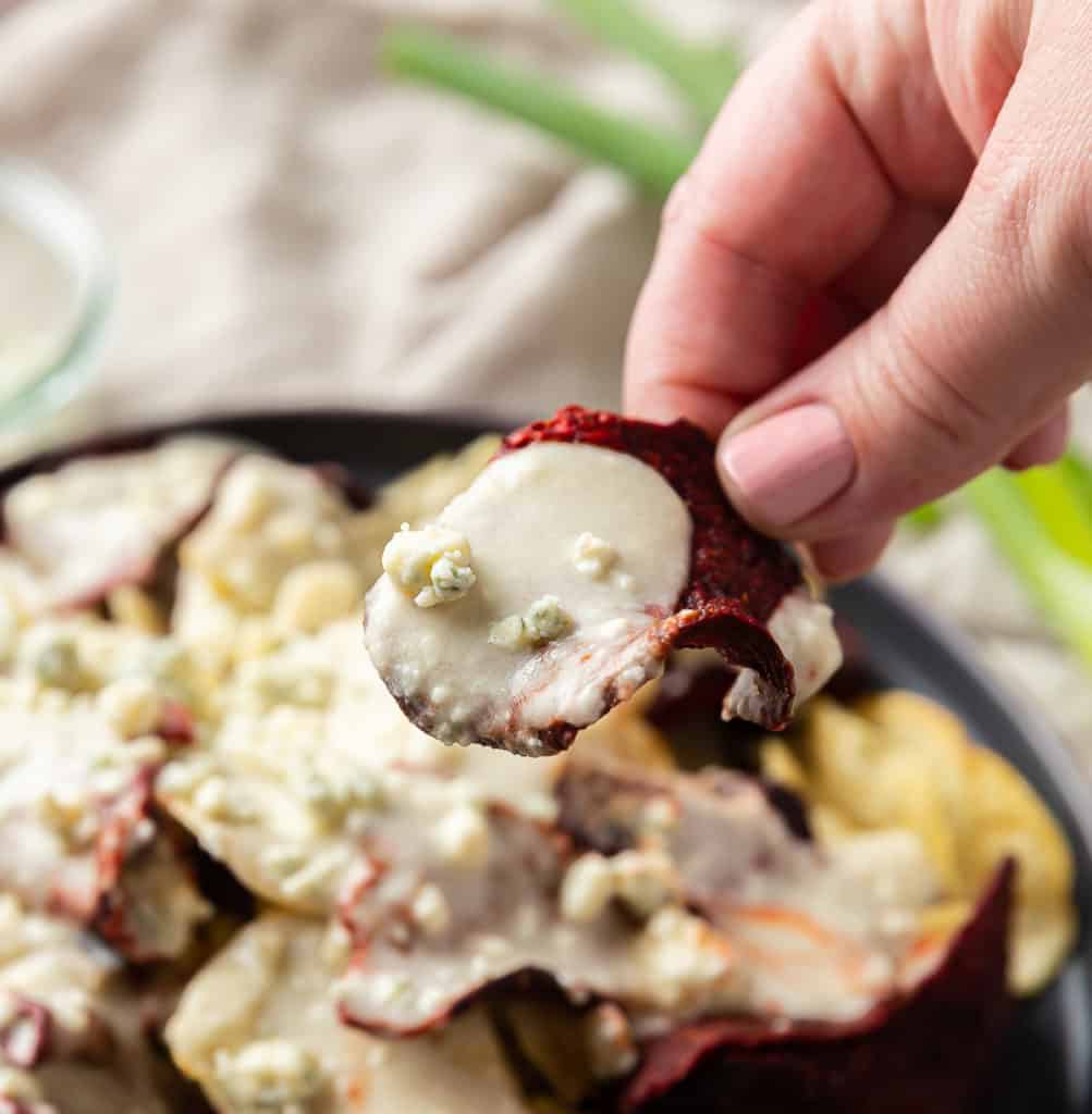 blue cheese sauce on a beet chip about to be eaten