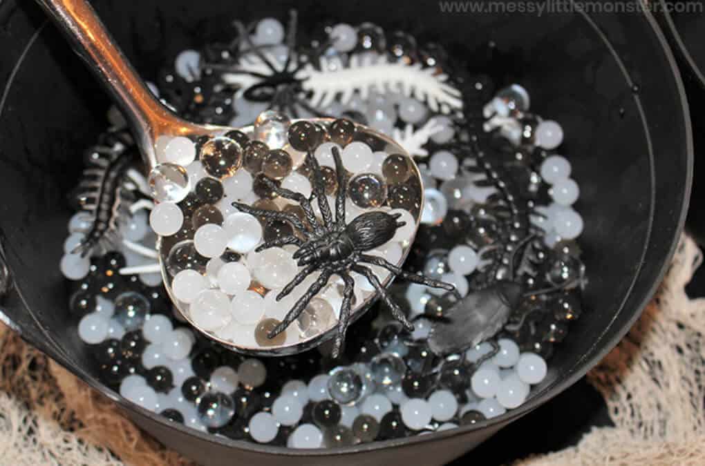 Halloween themed sensory bin with toy spiders and water beads