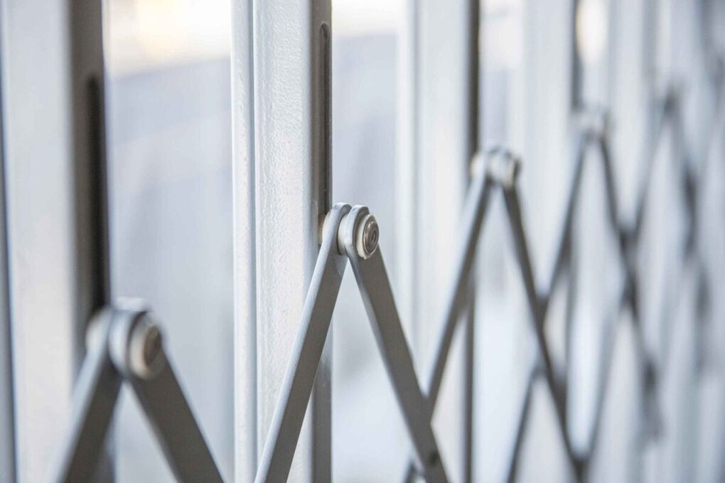 Close-up of scissor-style lattice joints on powder-coated retractable security gates.