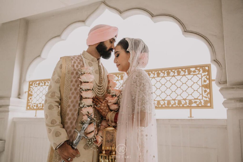 Manak and Vaani under a golden arch on their Sikh wedding day in Bangkok